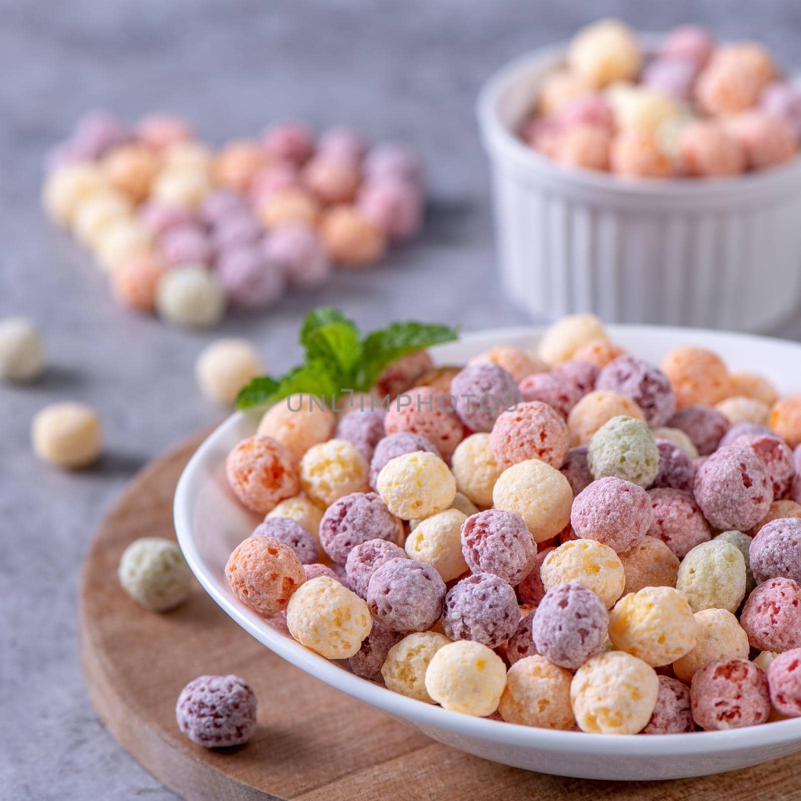 Colorful cereal corn balls mix, fruit flavor bowl sweets on gray cement background, close up, fresh, delicious and healthy breakfast, copy space design concept.