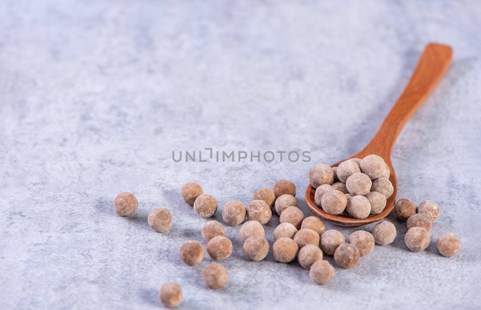 Dry raw brown tapioca pearls isolated on gray cement concrete background, close up, ingredient of making bubble boba tapioca milk tea.