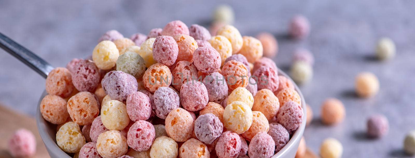 Colorful cereal corn balls mix, fruit flavor bowl sweets on gray cement background, close up, fresh, delicious and healthy breakfast, copy space design concept.