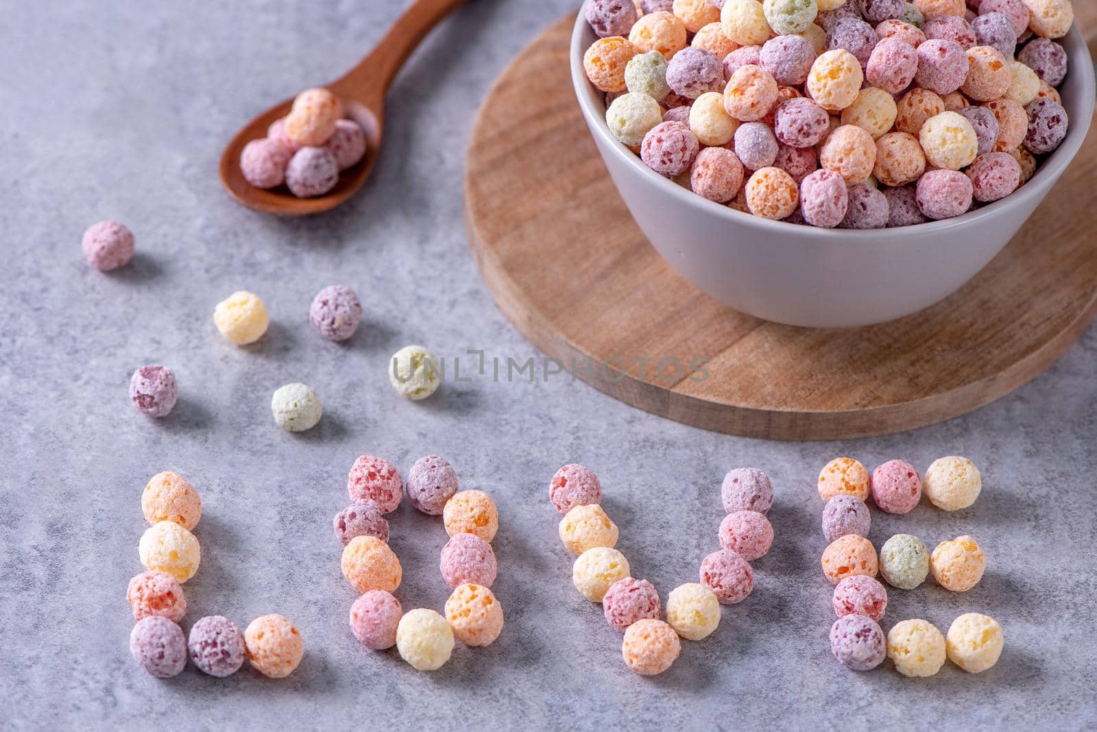 Colorful cereal corn balls mix, fruit flavor bowl sweets on gray cement background, close up, fresh, delicious and healthy breakfast, copy space design concept.