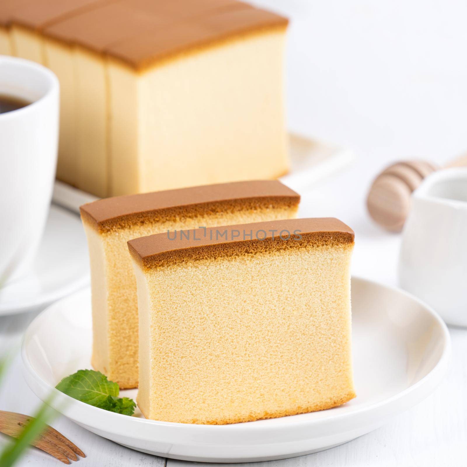 Castella (kasutera) - Beautiful delicious Japanese sliced sponge cake food on white plate over rustic white wooden table, close up, copy space design concept.