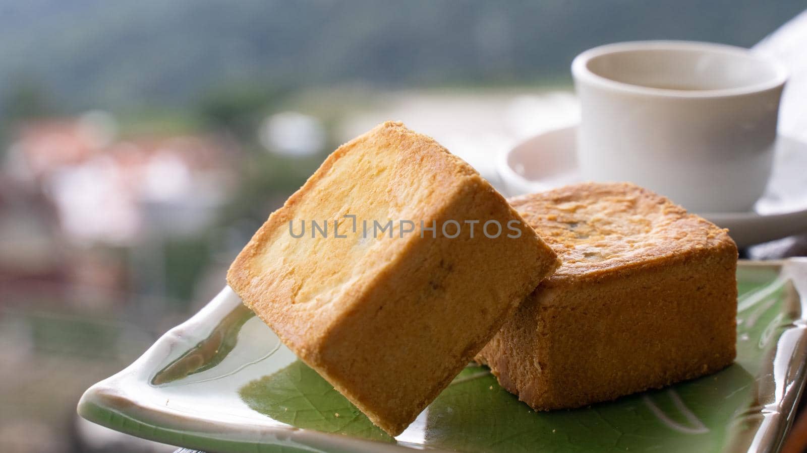 Delicious pineapple pastry in a plate for afternoon tea on wooden railing of a teahouse in Taiwan with beautiful landscape in background, close up.
