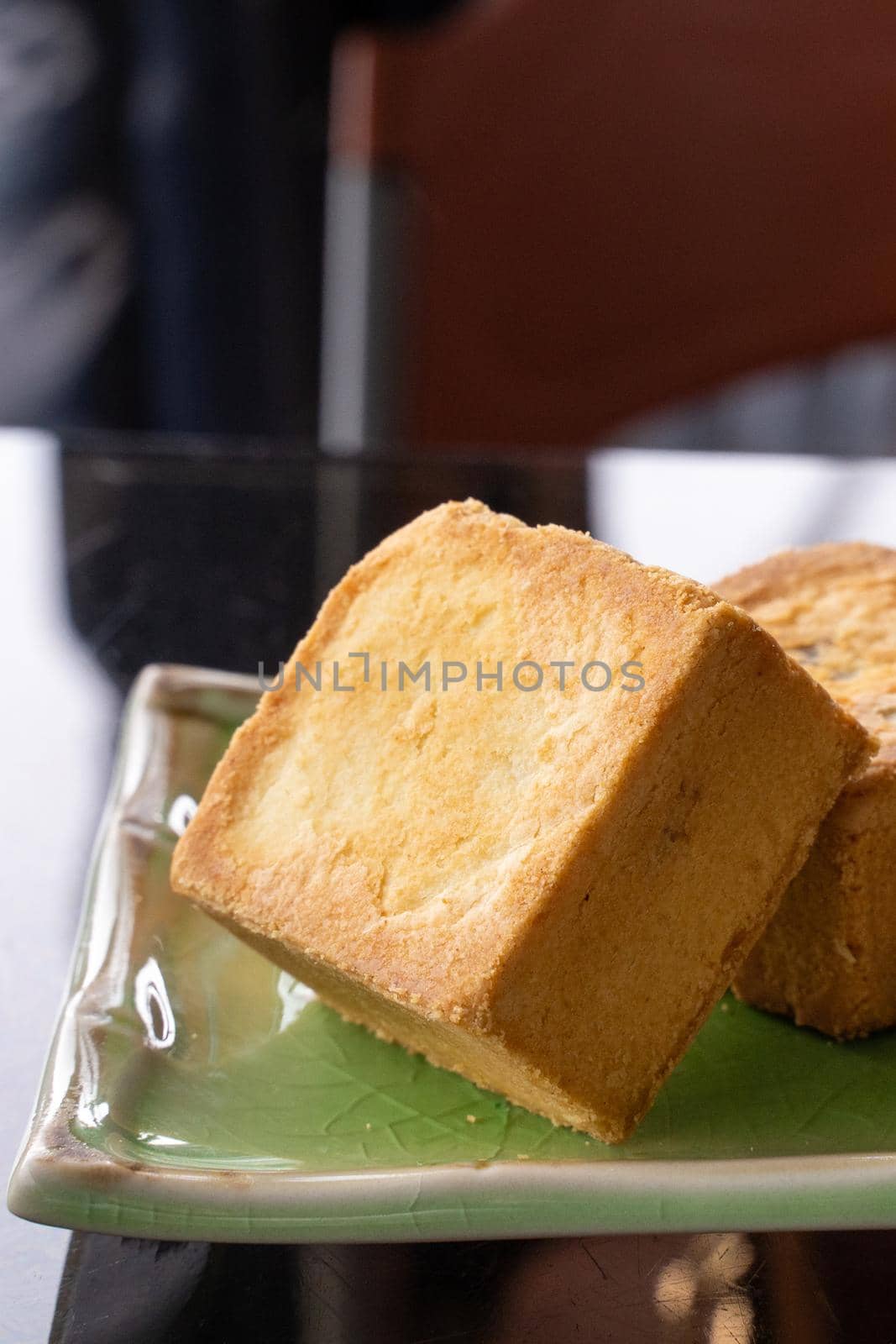 Delicious pineapple pastry in a plate for afternoon tea on wooden railing of a teahouse in Taiwan with beautiful landscape in background, close up.