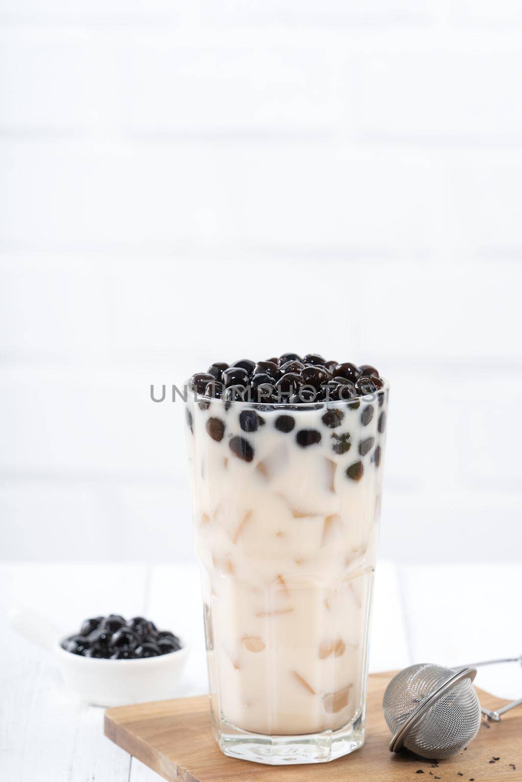 Bubble milk tea with tapioca pearl topping, famous Taiwanese drink on white wooden table background in drinking glass, close up, copy space