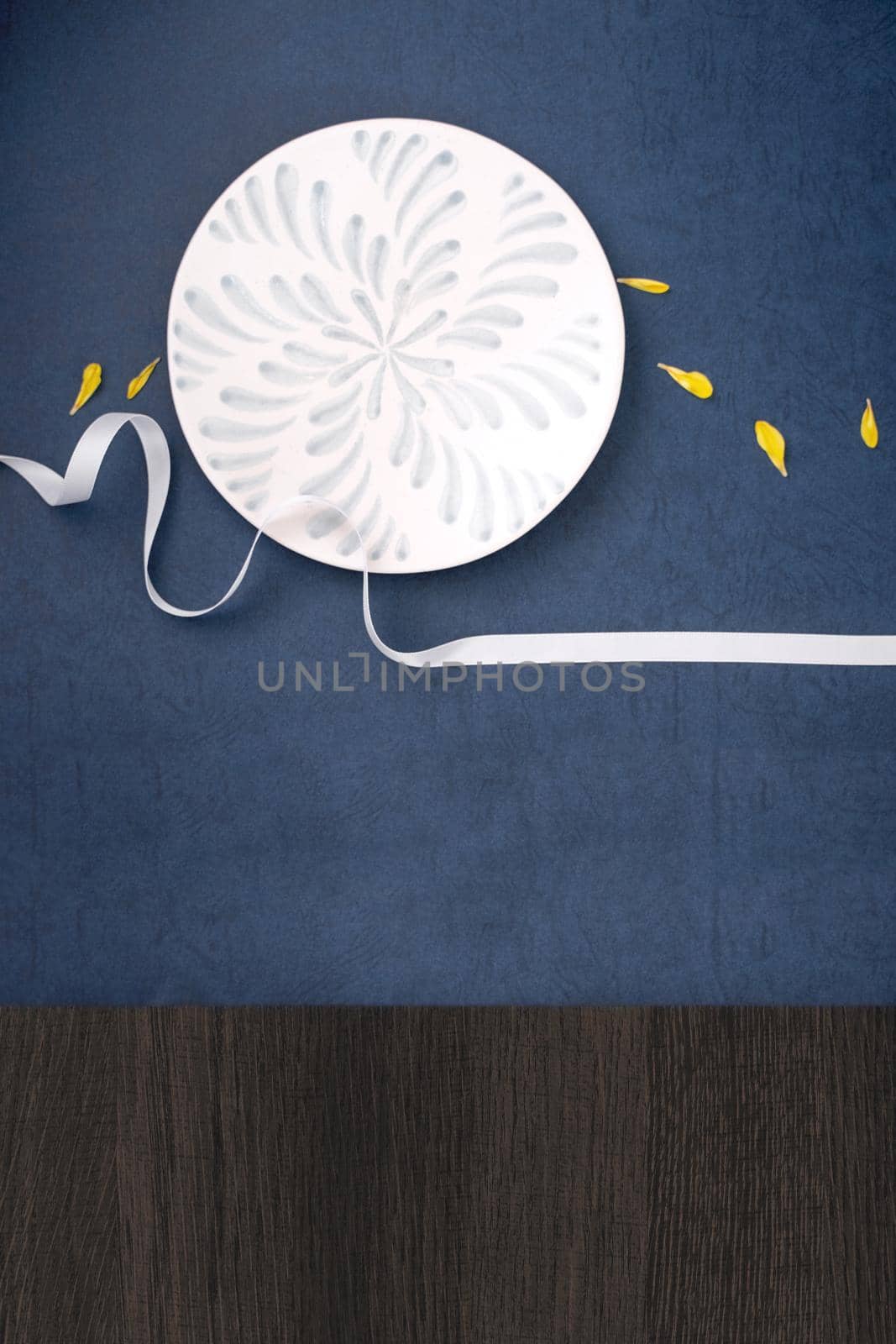 Conceptual Mid-Autumn Festival table background, symbol of moon, clouds and stars in the sky with plate, ribbon and yellow petal. Top view, flat lay.