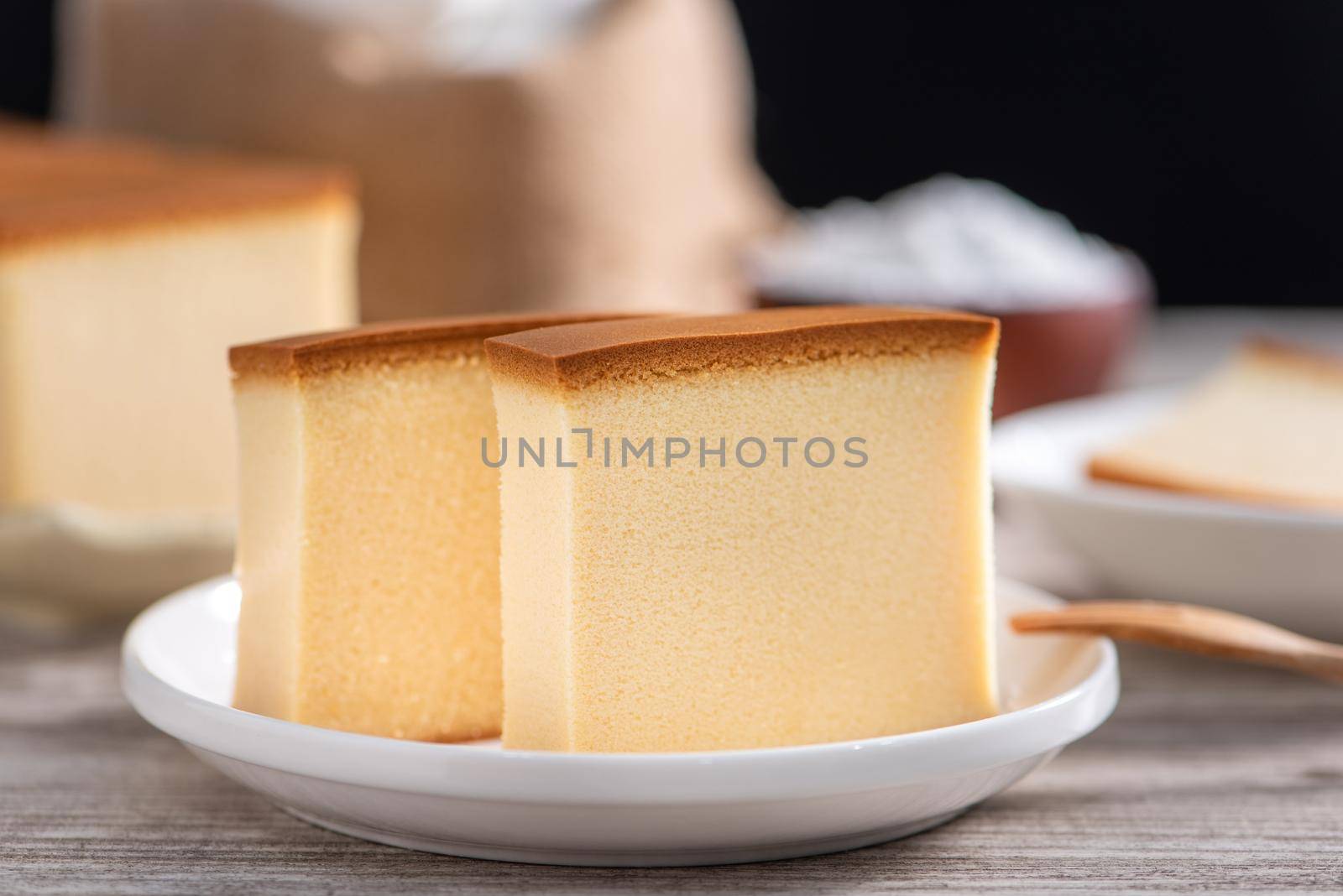 Castella (kasutera) - Delicious Japanese sliced sponge cake food on white plate over rustic wooden table, close up, healthy eating, copy space design.