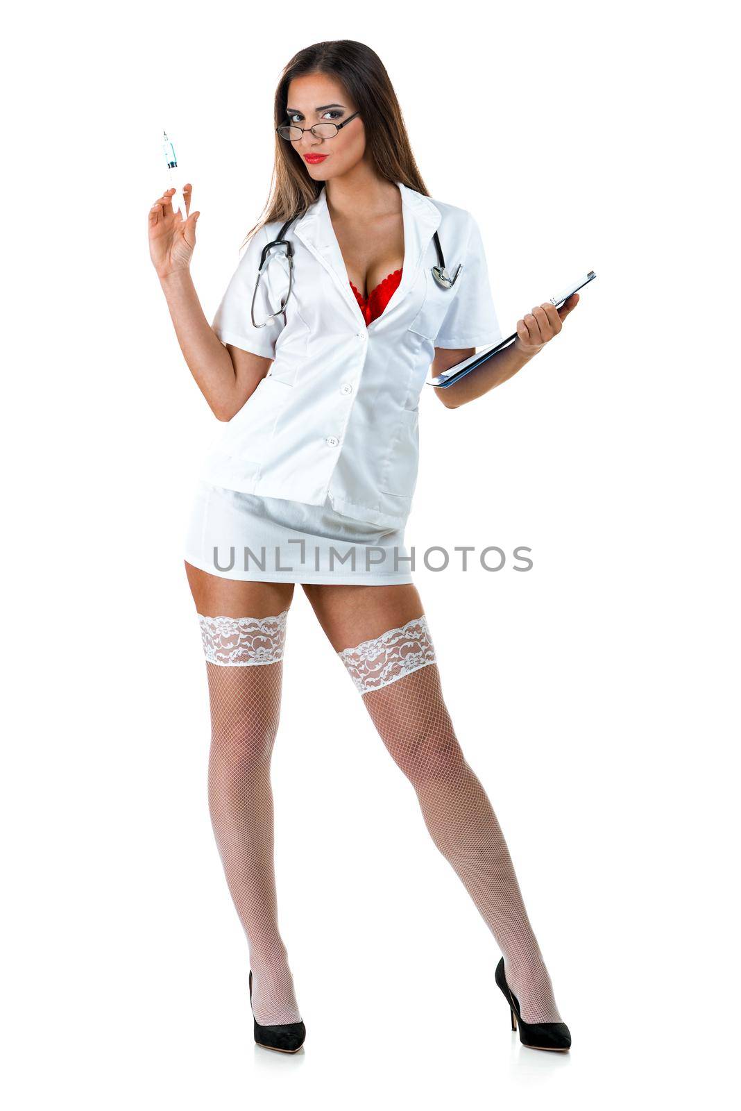 Beautiful smiling sexy nurse with stethoscope and injection in her hand, standing and posing in short skirt and stockings thigh high. Isolated on white background. Looking at camera.