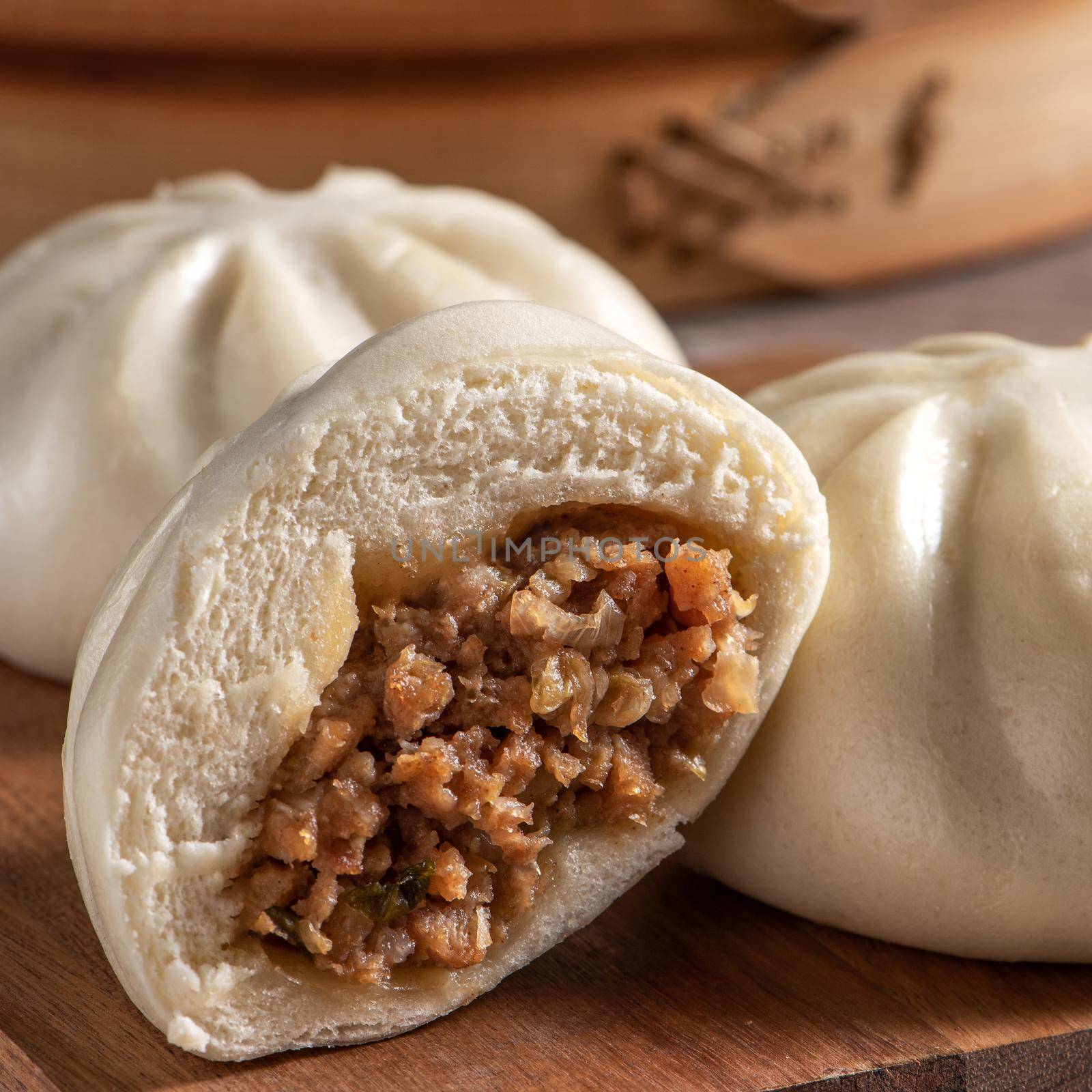 Delicious baozi, Chinese steamed meat bun is ready to eat on serving plate and steamer, close up, copy space product design concept.
