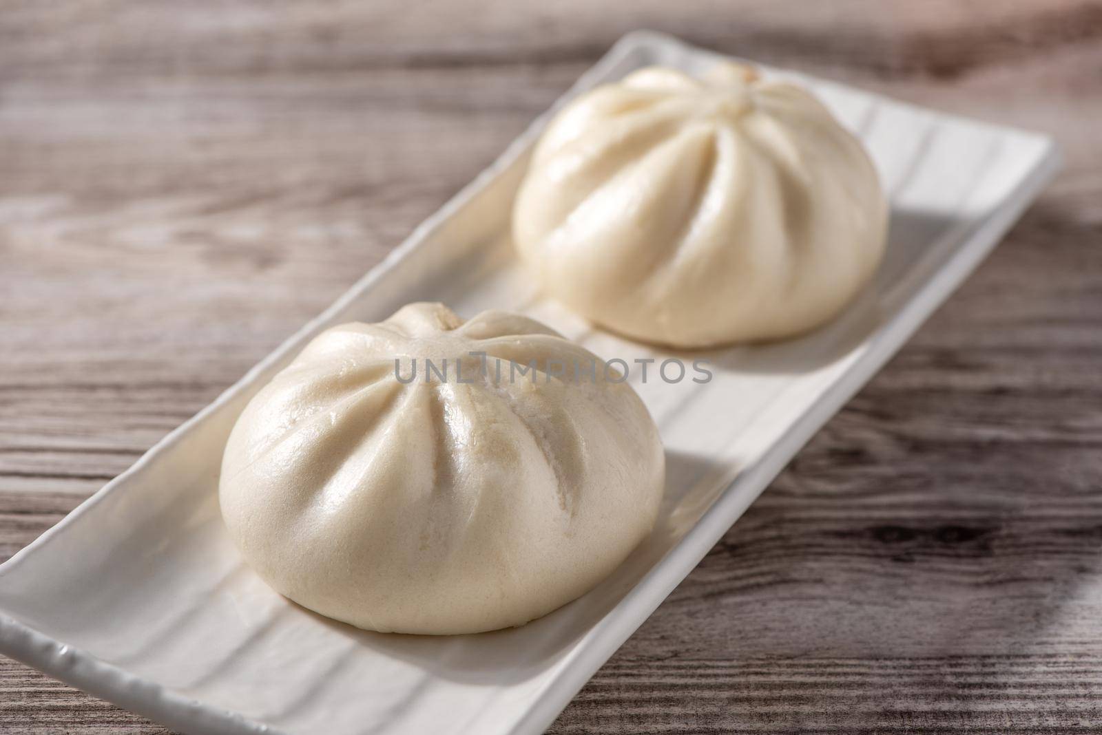 Delicious baozi, Chinese steamed meat bun is ready to eat on serving plate and steamer, close up, copy space product design concept.