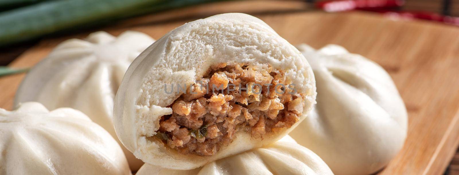 Delicious baozi, Chinese steamed meat bun is ready to eat on serving plate and steamer, close up, copy space product design concept.