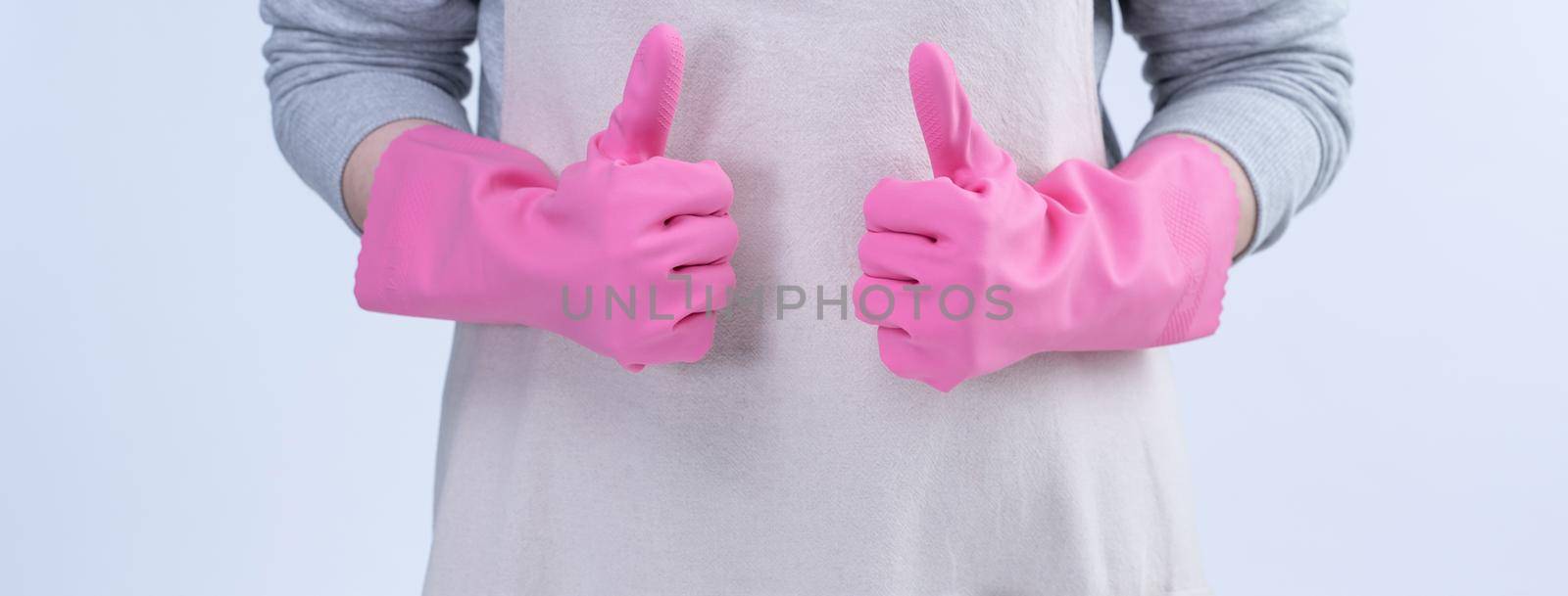 Young woman housekeeper in apron is wearing pink gloves to clean the table, concept of preventing virus infection, housekeeping service, close up.