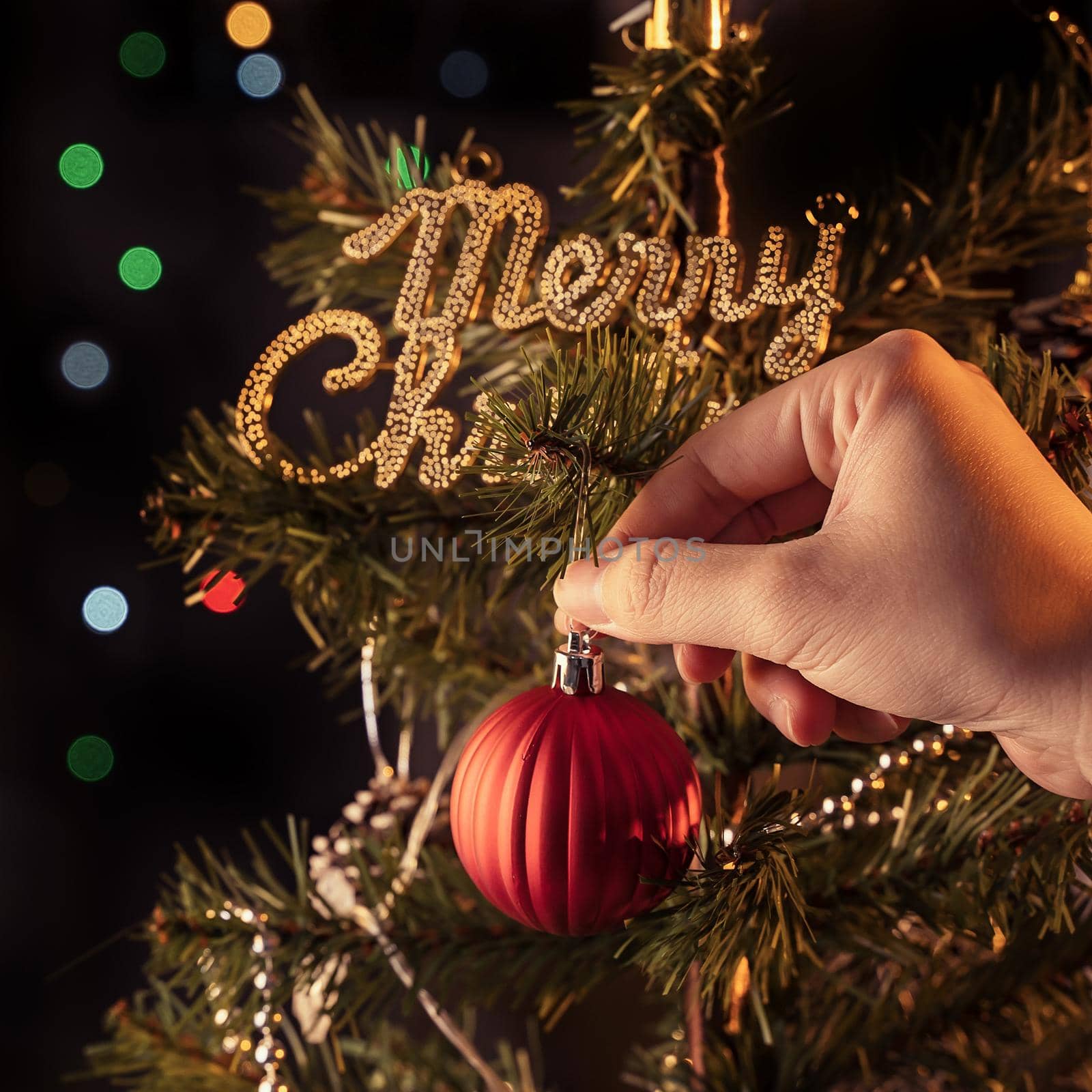 Christmas background concept- beautiful decor bauble hanging on the Christmas tree with sparkling light spot, blurry dark black background, copy space, close up.