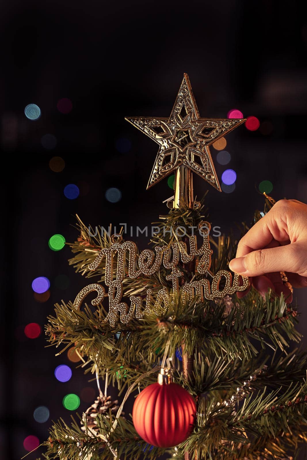 Christmas background concept- beautiful decor bauble hanging on the Christmas tree with sparkling light spot, blurry dark black background, copy space, close up.