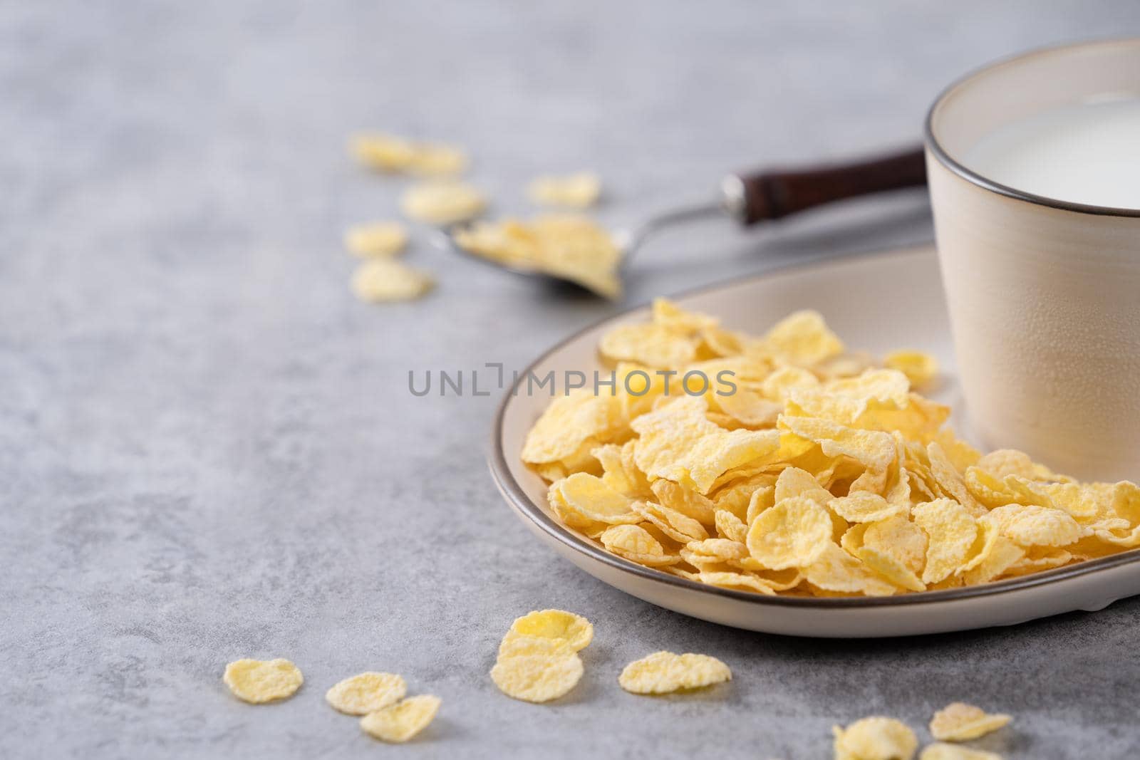 Corn flakes bowl sweeties with milk on gray cement background, close up, fresh and healthy breakbast design concept.