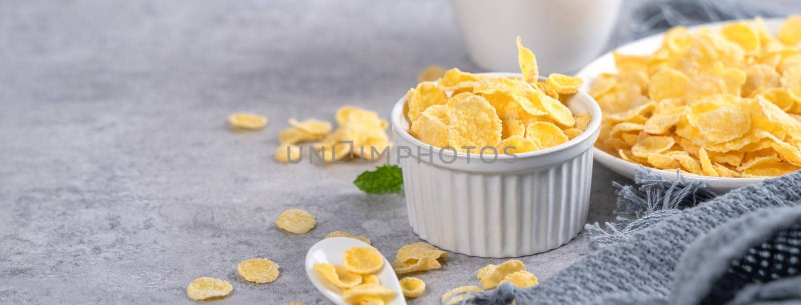 Corn flakes bowl sweeties with milk on gray cement background, close up, fresh and healthy breakbast design concept.