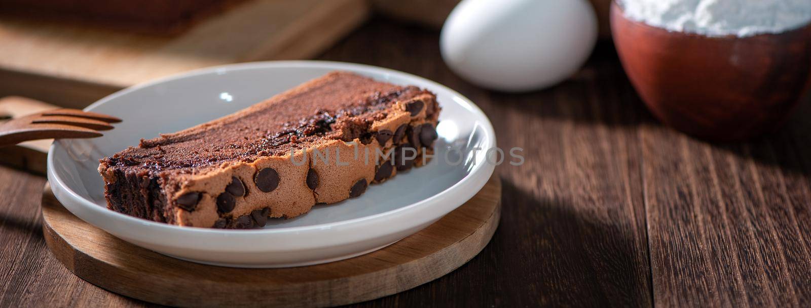 Chocolate flavor Taiwanese traditional sponge cake (Taiwanese castella kasutera) on a wooden tray background table with ingredients, close up.