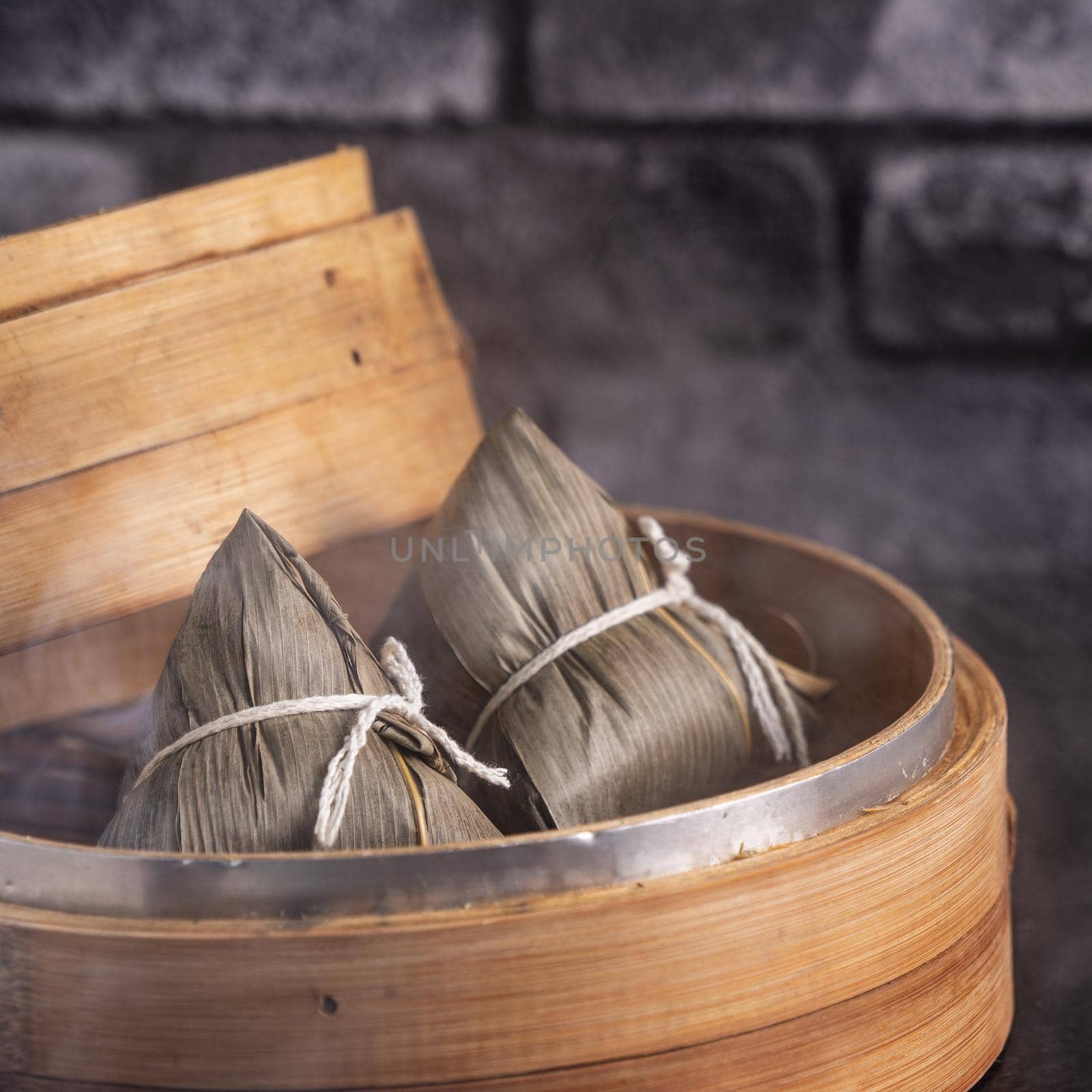 Rice dumpling, zongzi - Chinese rice dumpling zongzi on black brick background slate table, concept of Dragon Boat Festival traditional food, close up.