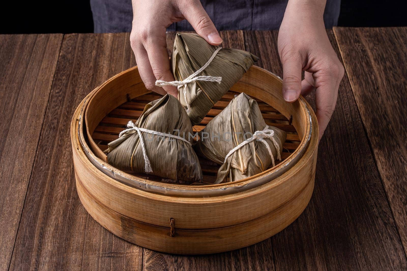 Rice dumpling, zongzi - Dragon Boat Festival, Bunch of Chinese traditional cooked food in steamer on wooden table over black background, close up, copy space