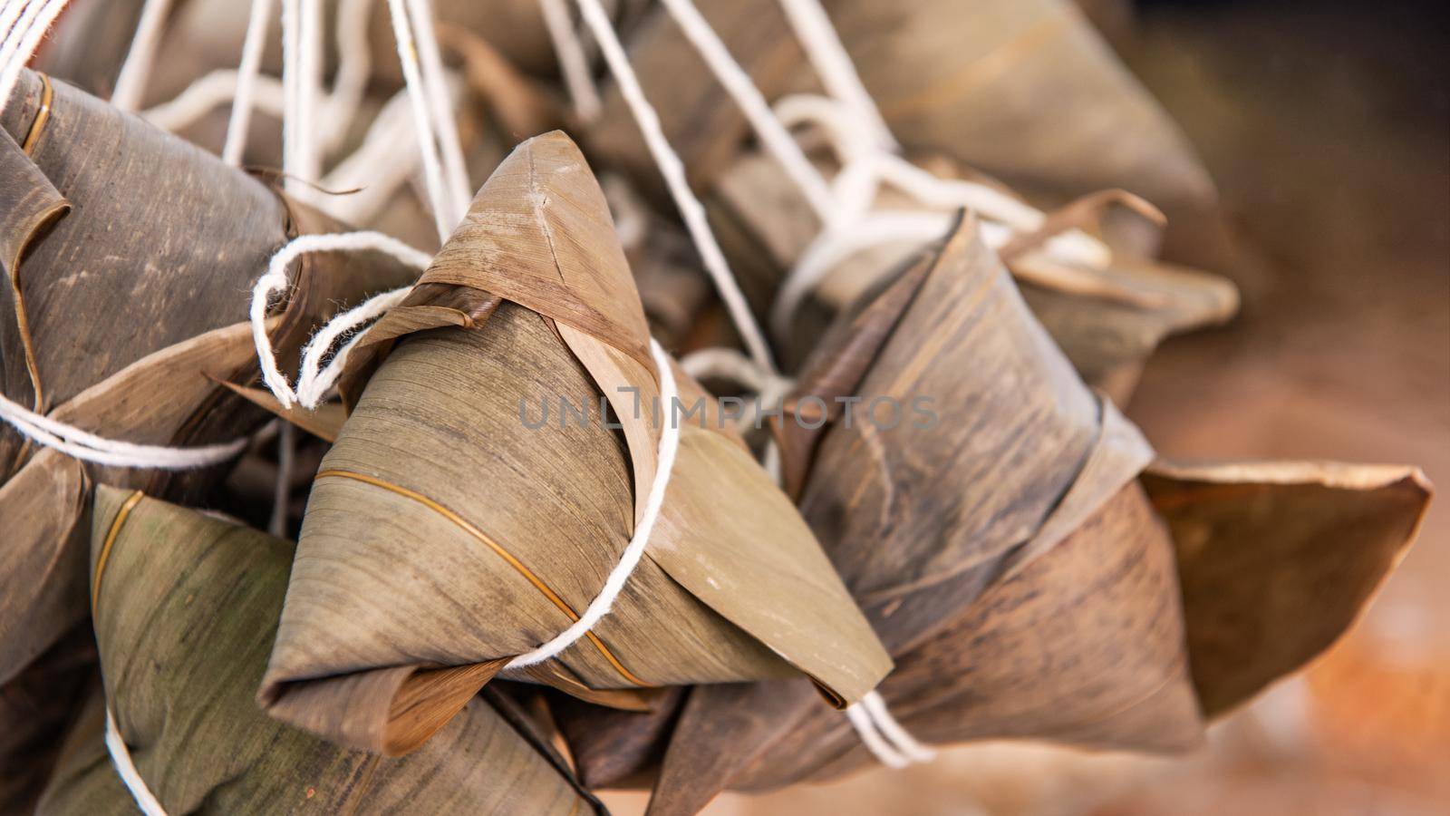 Rice dumpling - Chinese zongzi food in a steamer on wooden table with red brick wall, window background at home for Dragon Boat Festival concept, close up.