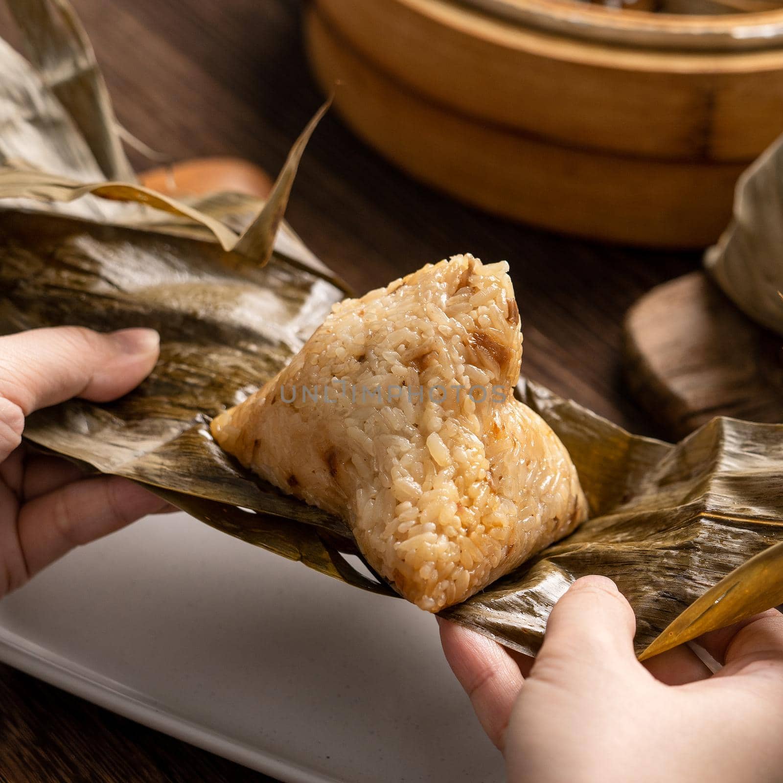 Eating zongzi - Dragon Boat Festival Rice dumpling young Asian woman eating Chinese traditional food on wooden table at home celebration, close up