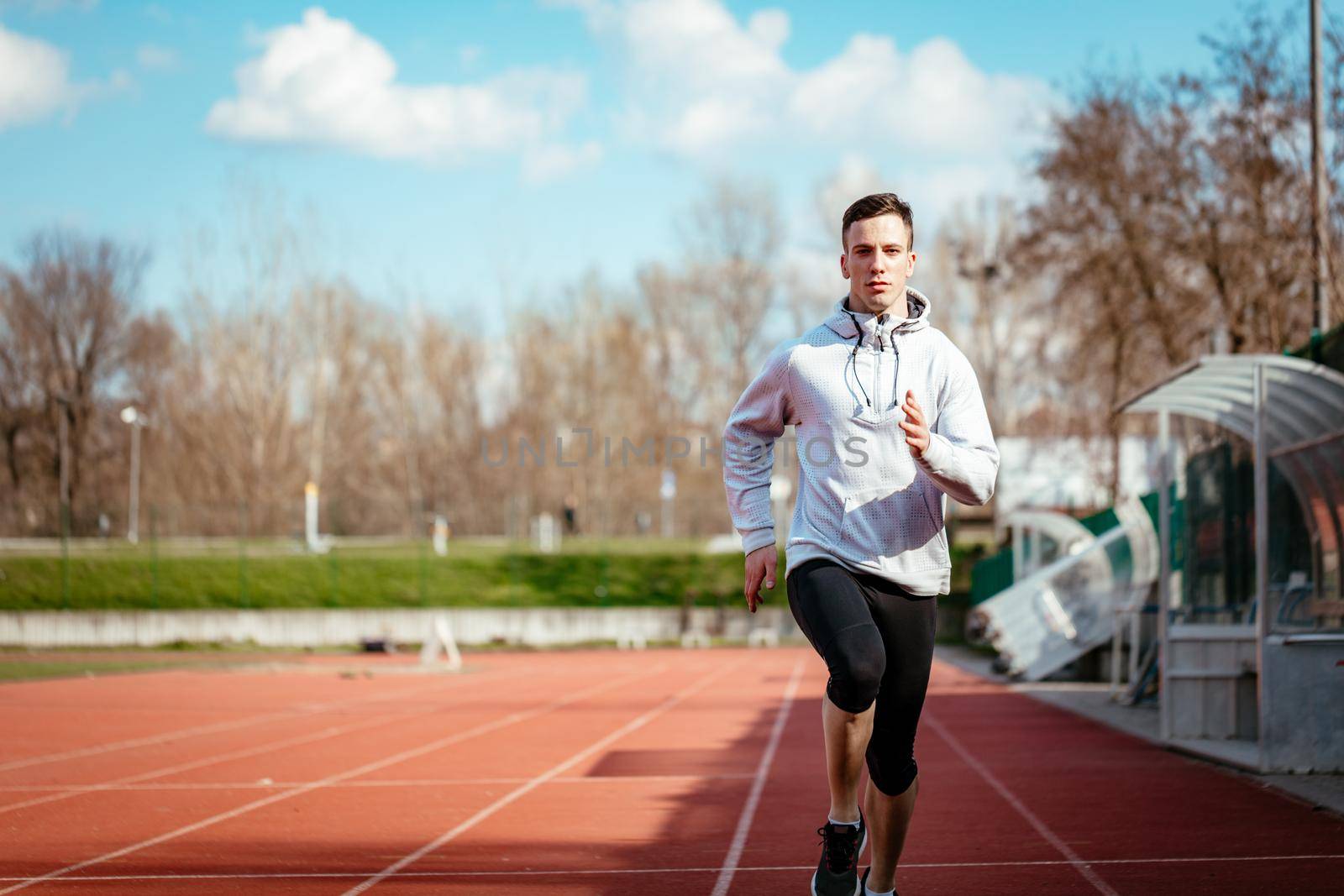 Athletic fit young sport man in full body length on tartan track on the stadium.