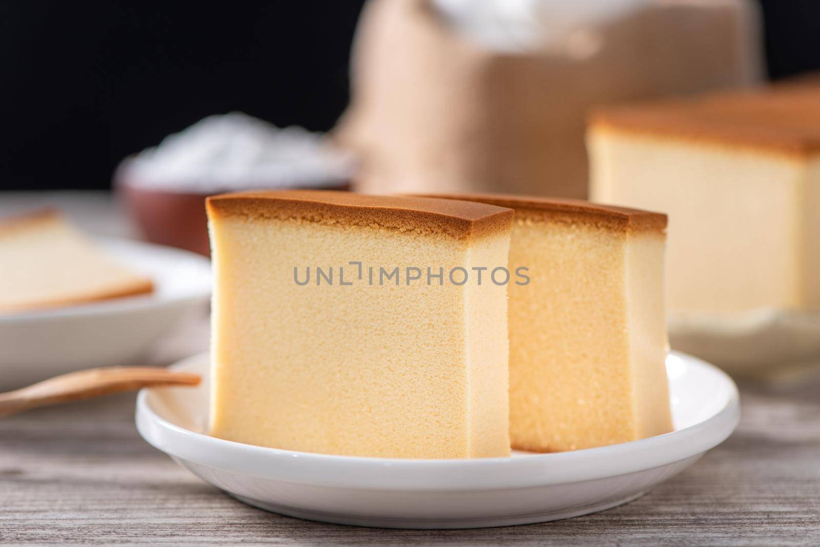 Castella - Delicious Japanese sliced sponge cake food on white plate over rustic wooden table, close up, healthy eating, copy space design.