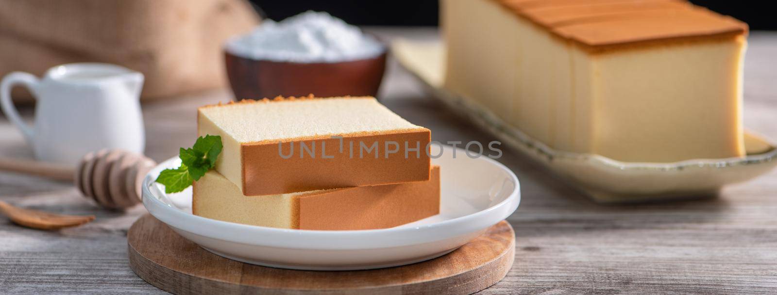 Castella - Delicious Japanese sliced sponge cake food on white plate over rustic wooden table, close up, healthy eating, copy space design.