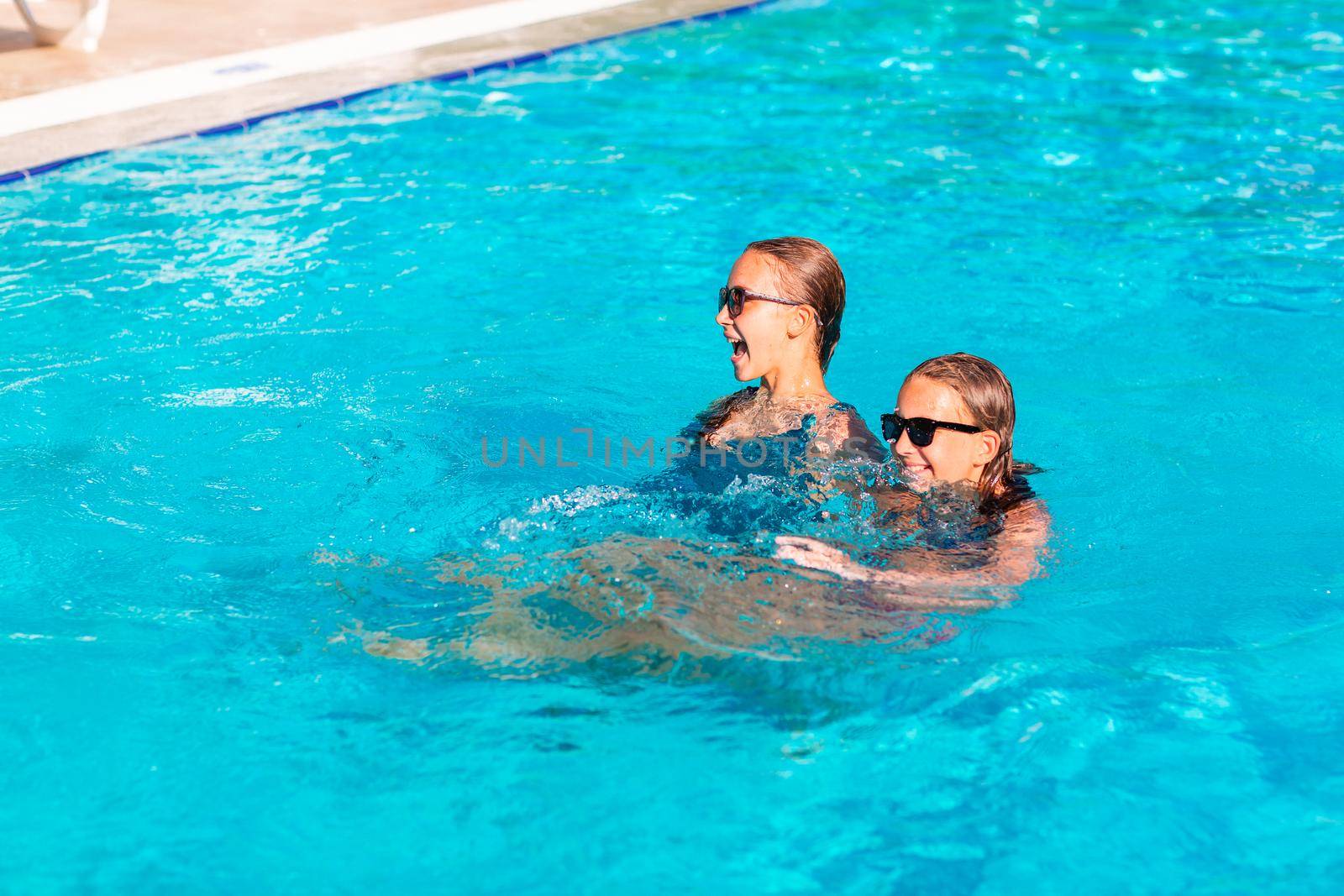 Happy beautiful girls having fun at the pool at the resort