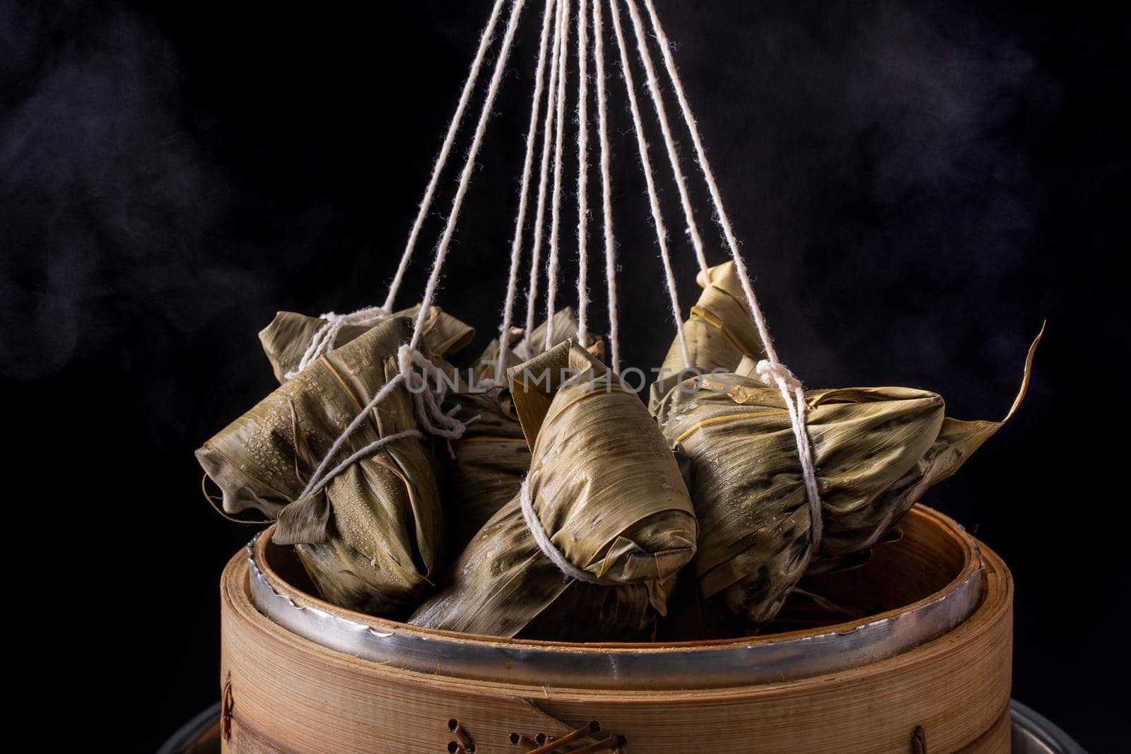 Rice dumpling, zongzi - Dragon Boat Festival, Bunch of Chinese traditional cooked food in steamer on wooden table over black background, close up, copy space