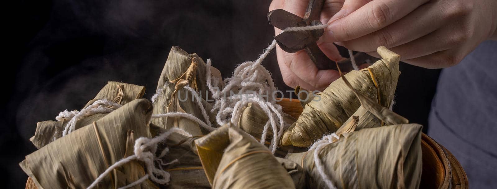 Rice dumpling, zongzi - Dragon Boat Festival, Bunch of Chinese traditional cooked food in steamer on wooden table over black background, close up, copy space