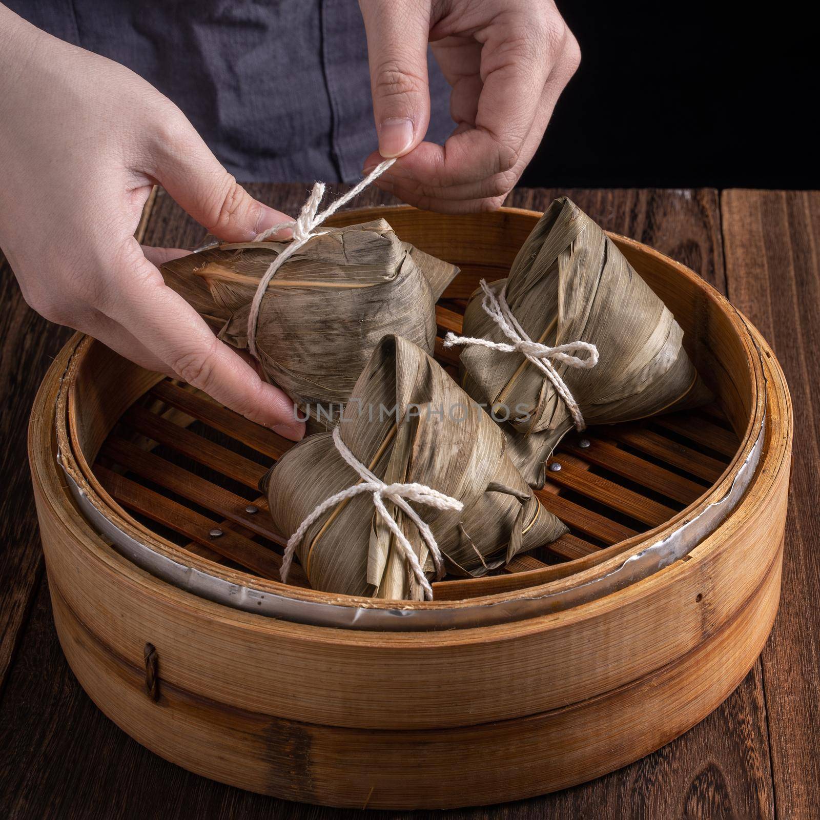 Rice dumpling, zongzi - Dragon Boat Festival, Bunch of Chinese traditional cooked food in steamer on wooden table over black background, close up, copy space