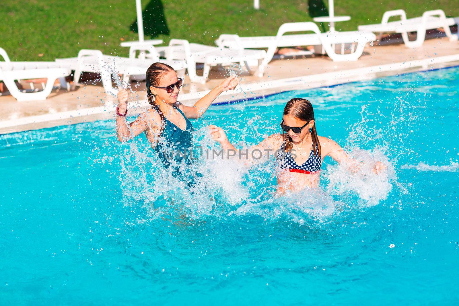 Happy beautiful girls having fun at the pool at the resort