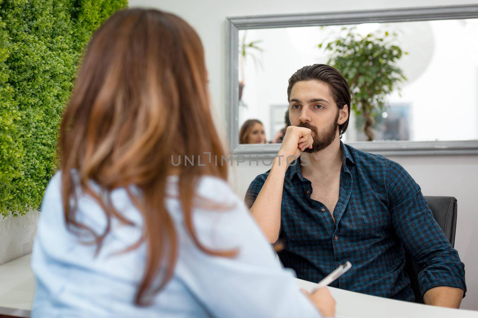 A young man gives an interview for a job, and the data is taken by a young woman.