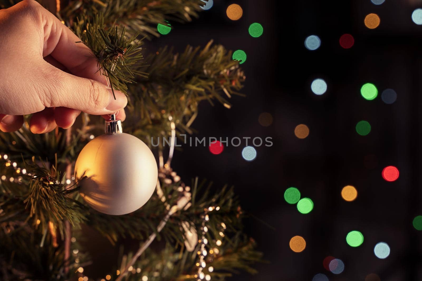 Christmas background concept- beautiful decor bauble hanging on the Christmas tree with sparkling light spot, blurry dark black background, copy space, close up.