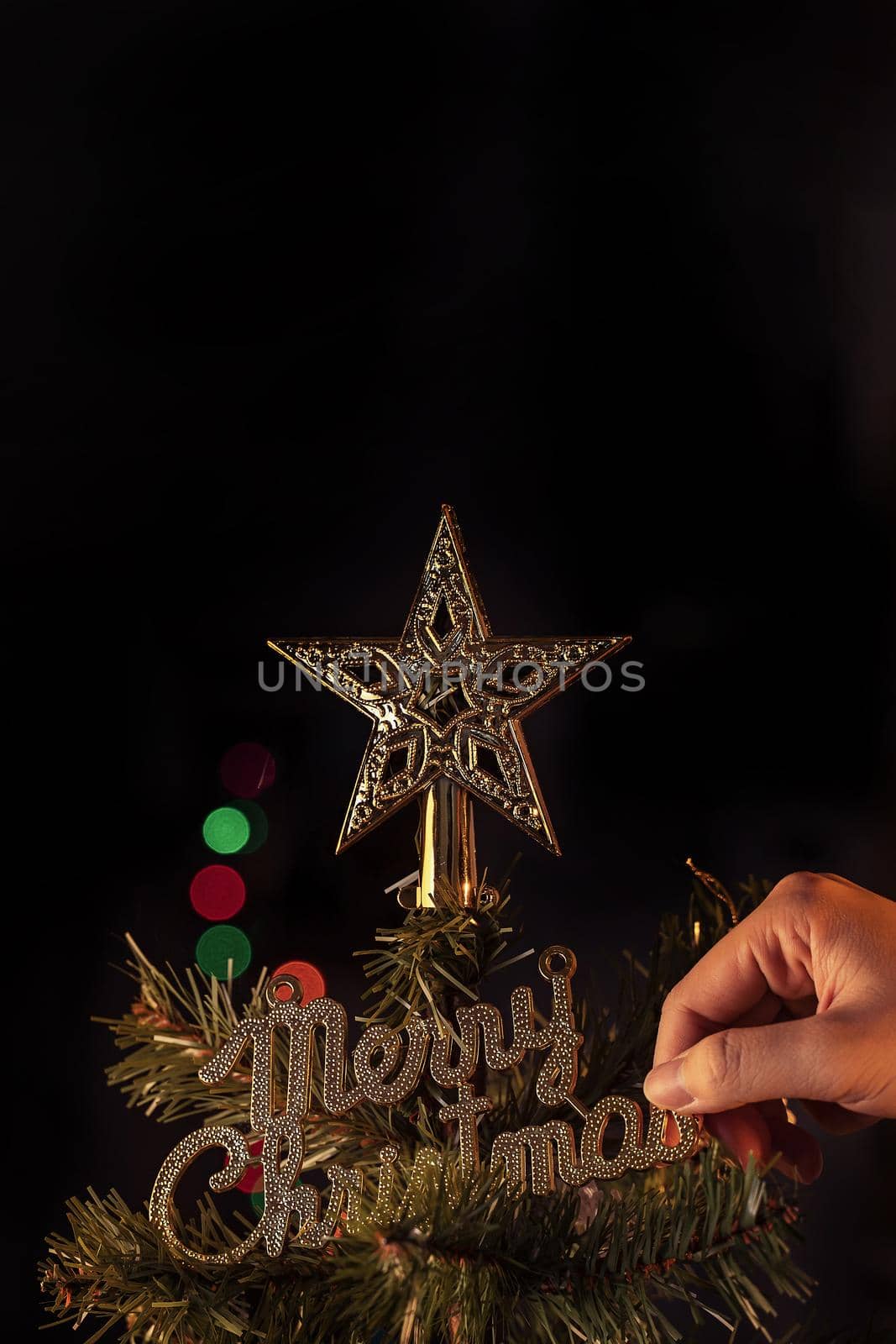 Christmas background concept- beautiful decor bauble hanging on the Christmas tree with sparkling light spot, blurry dark black background, copy space, close up.