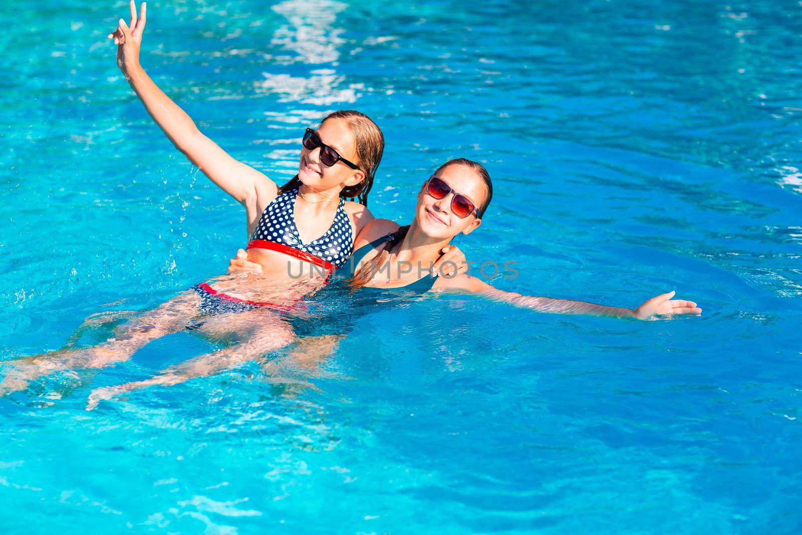 Happy beautiful girls having fun at the pool at the resort