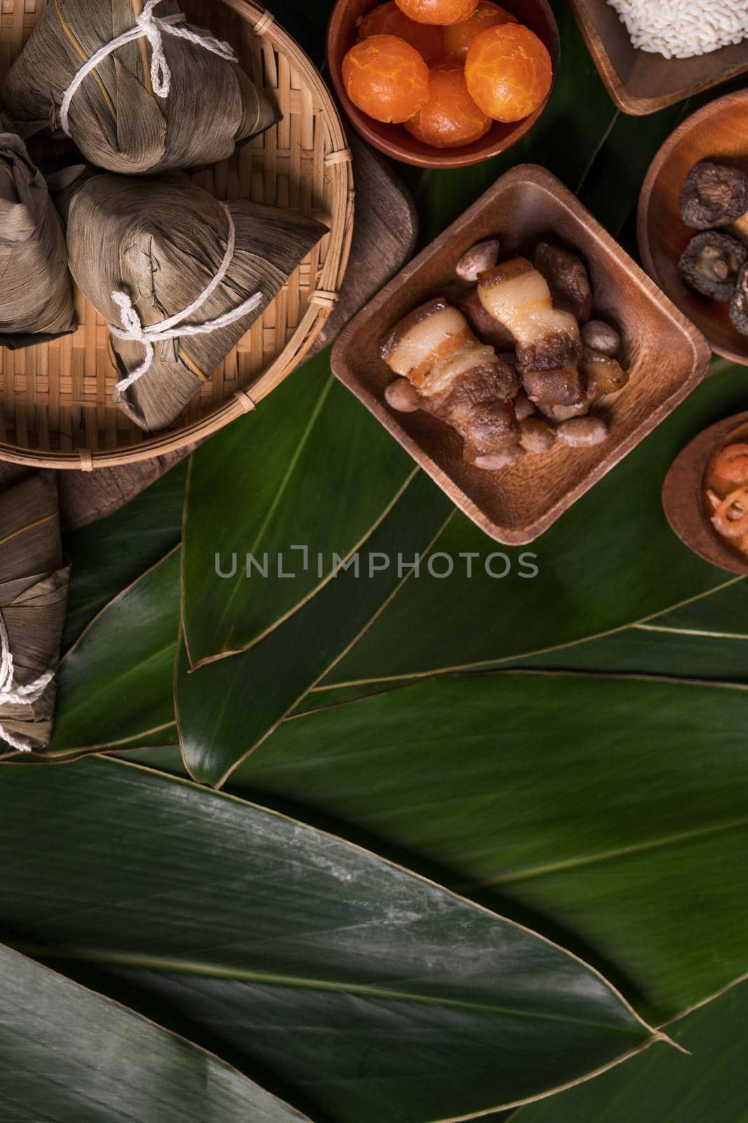 Rice dumpling, zongzi - Traditional Chinese food on green leaf background of Dragon Boat Festival, Duanwu Festival, top view, flat lay design concept. by ROMIXIMAGE