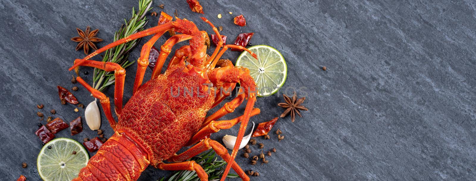 Cooked boiled lobster, delicious dinner seafood meal set with knife and fork on black stone slate background, restaurant menu design, top view, overhead