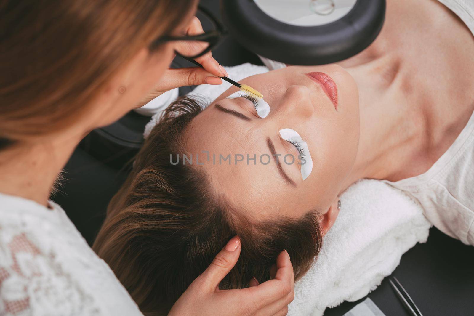 Beautician preparing model for applying extended eyelashes. 