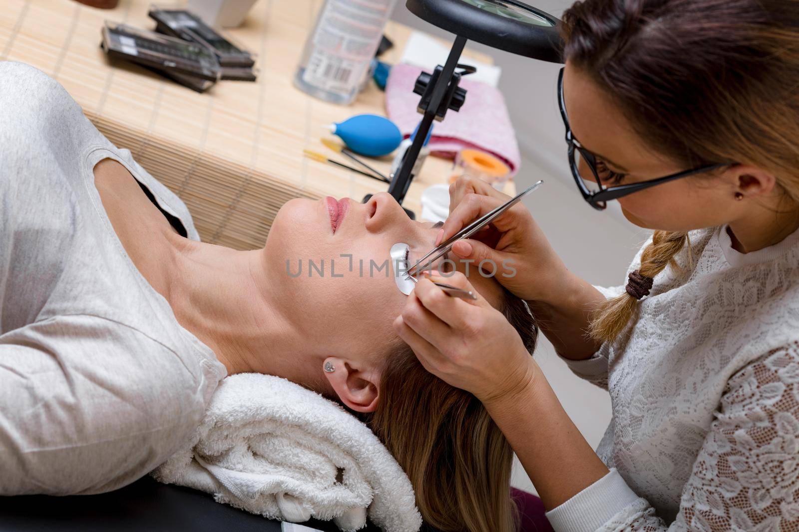 Beautician applying extended eyelashes to model at the beauty salon.