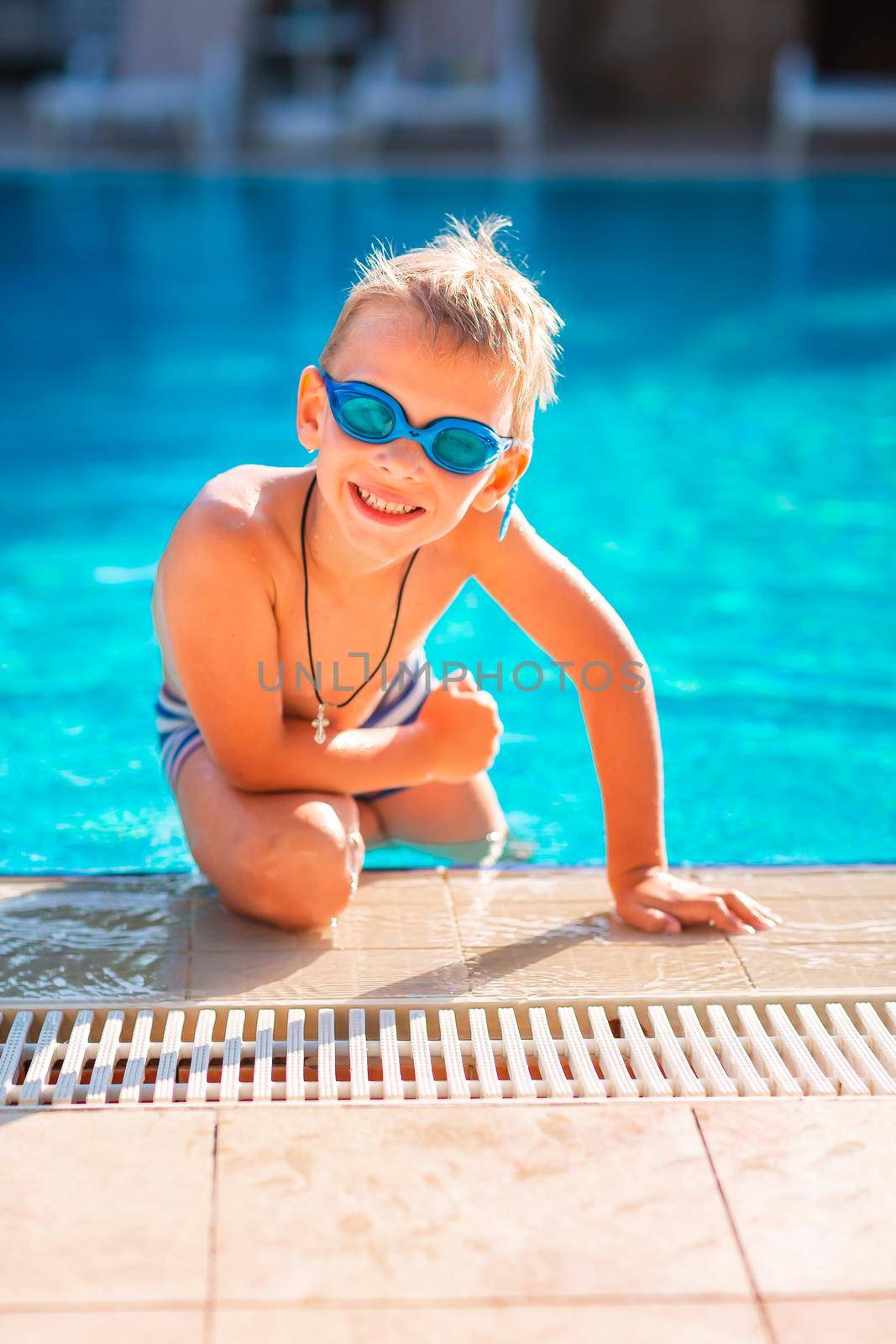 Cute happy little boy in goggles swimming and snorking in the swimming pool. Swimming for kids concept