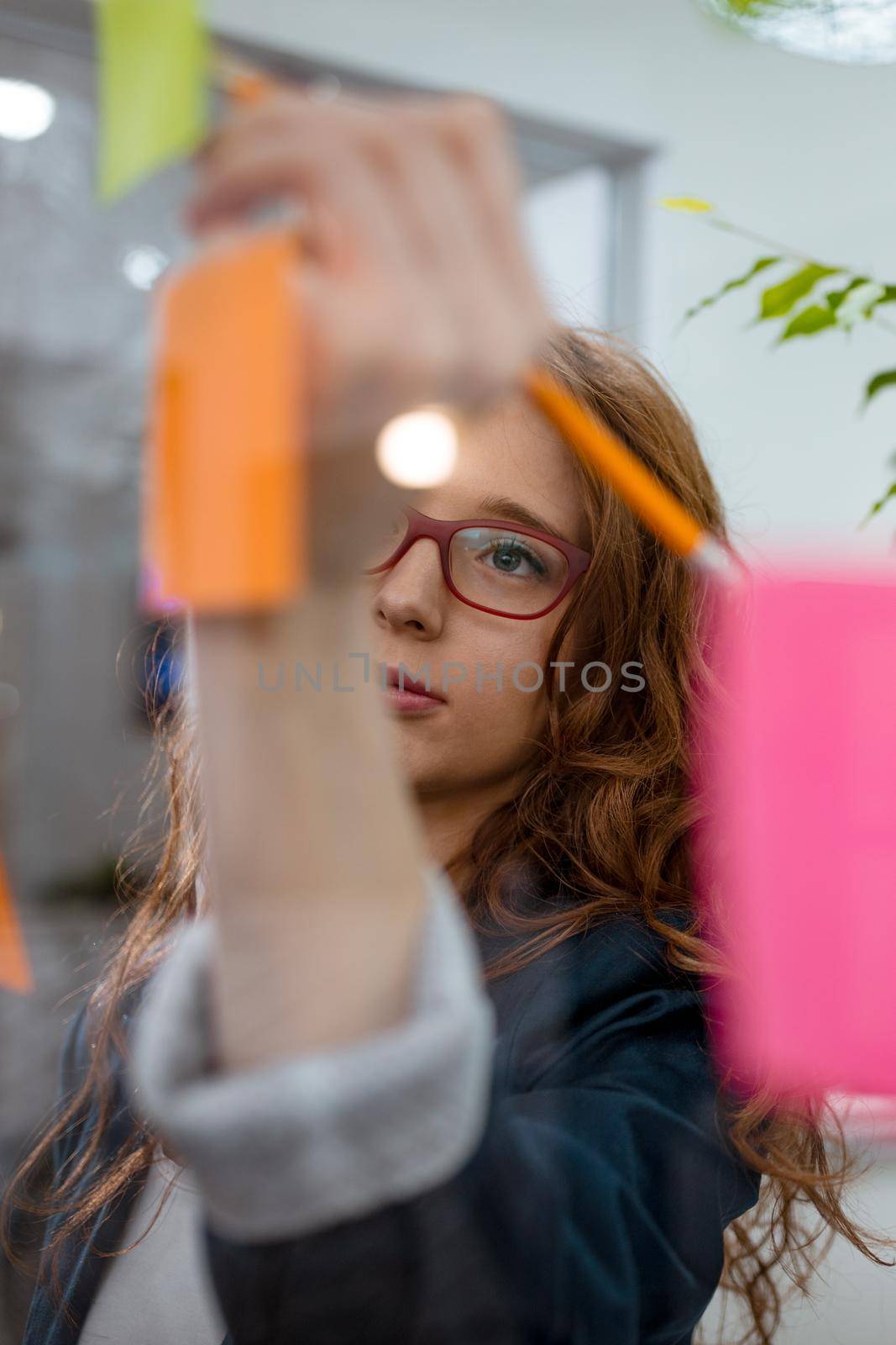 Creative female professionals executive standing at the office behind glass wall with sticky notes.