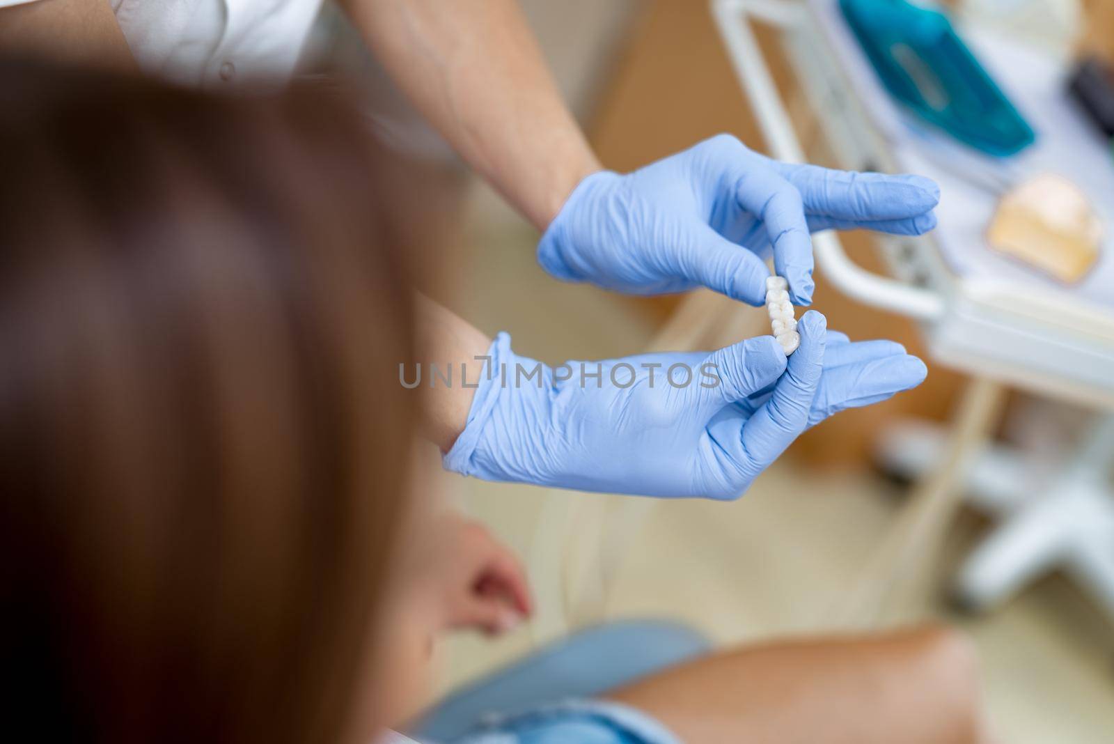 Dentist showing porcelain crowns to the patient. Close-up. Unrecognizable people.