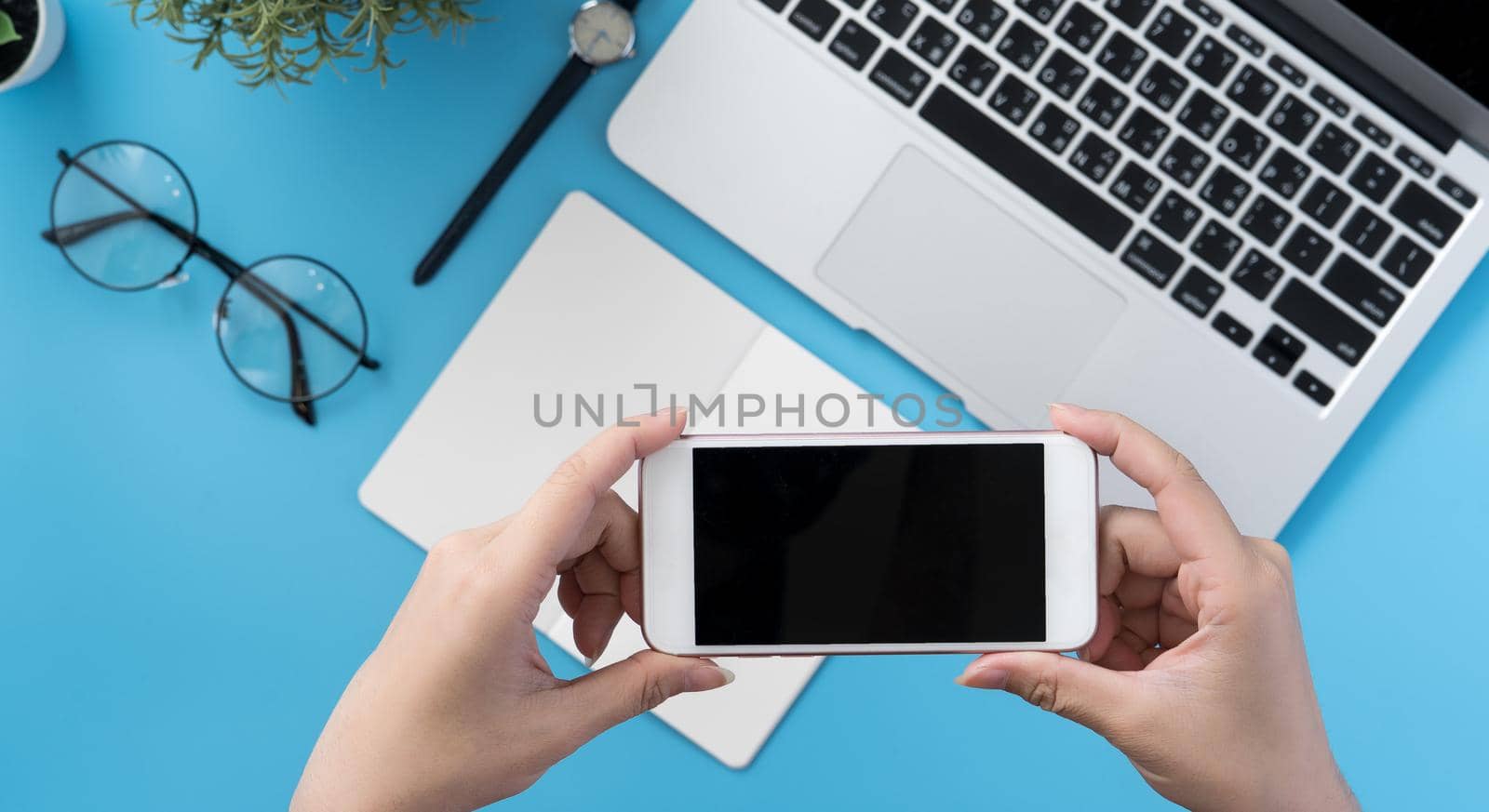 Social network connecting office table concept with fashion accessories, minimal interior with a woman holding smartphone, top view, flat lay, mockup, copy space
