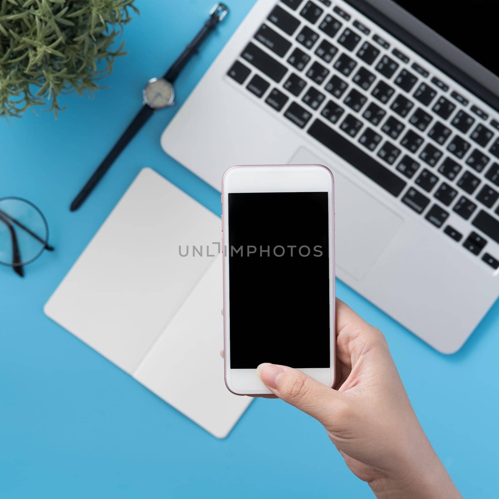 Social network connecting office table concept with fashion accessories, minimal interior with a woman holding smartphone, top view, flat lay, mockup, copy space
