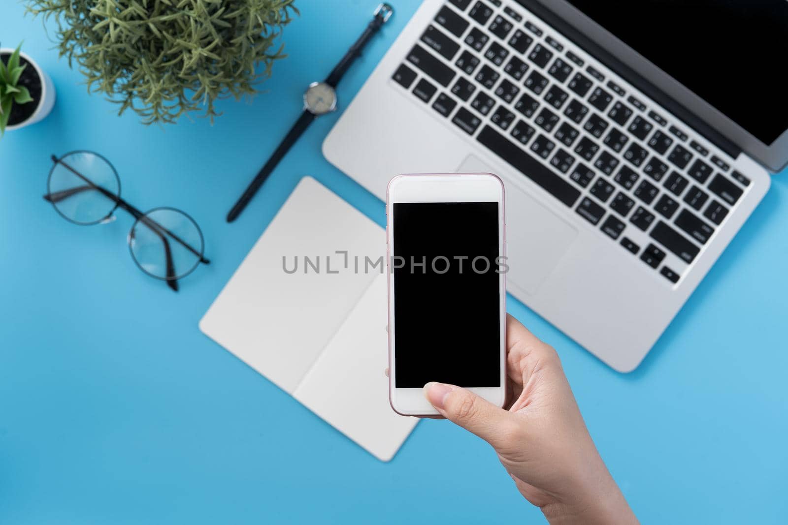 Social network connecting office table concept with fashion accessories, minimal interior with a woman holding smartphone, top view, flat lay, mockup, copy space