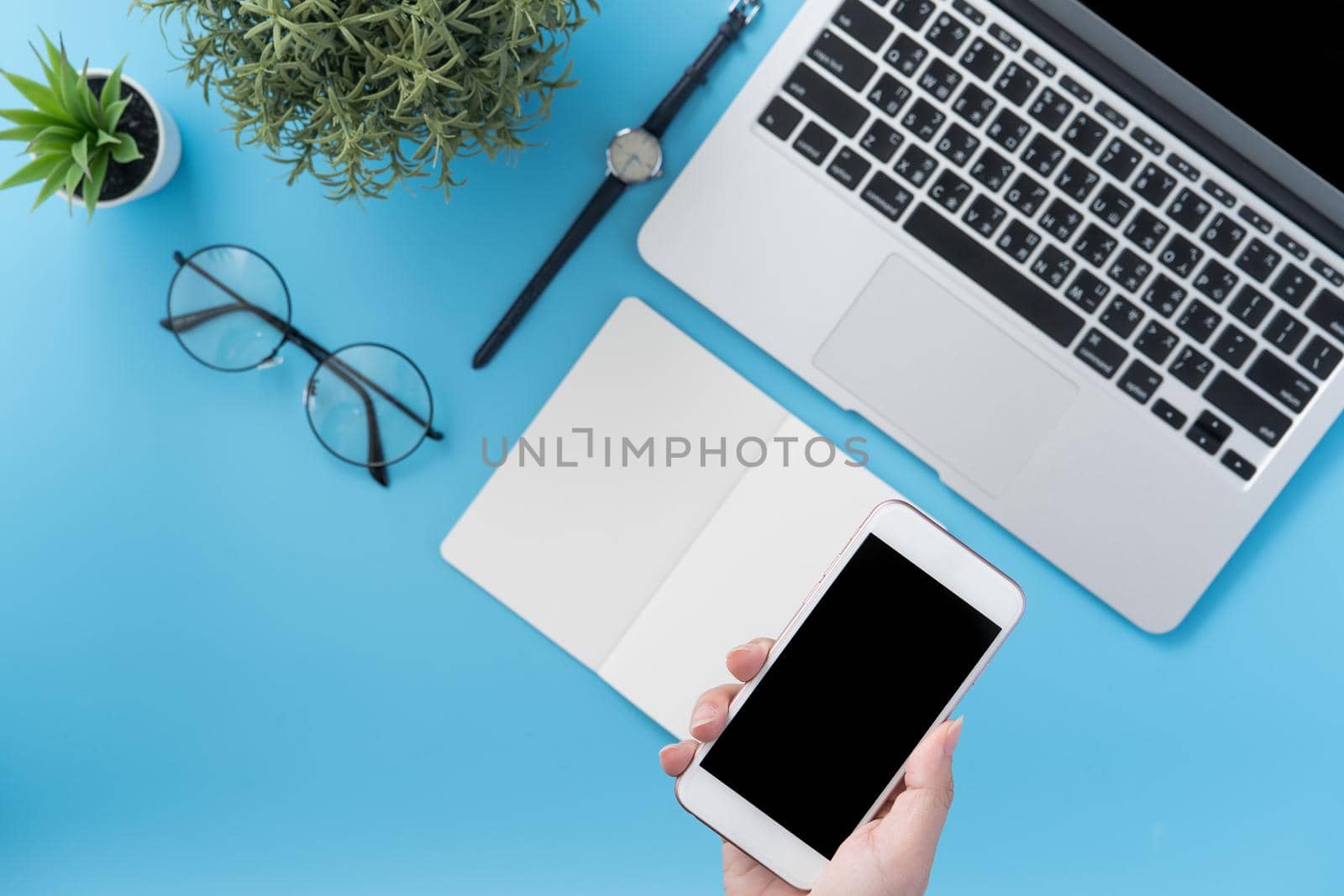 Social network connecting office table concept with fashion accessories, minimal interior with a woman holding smartphone, top view, flat lay, mockup, copy space