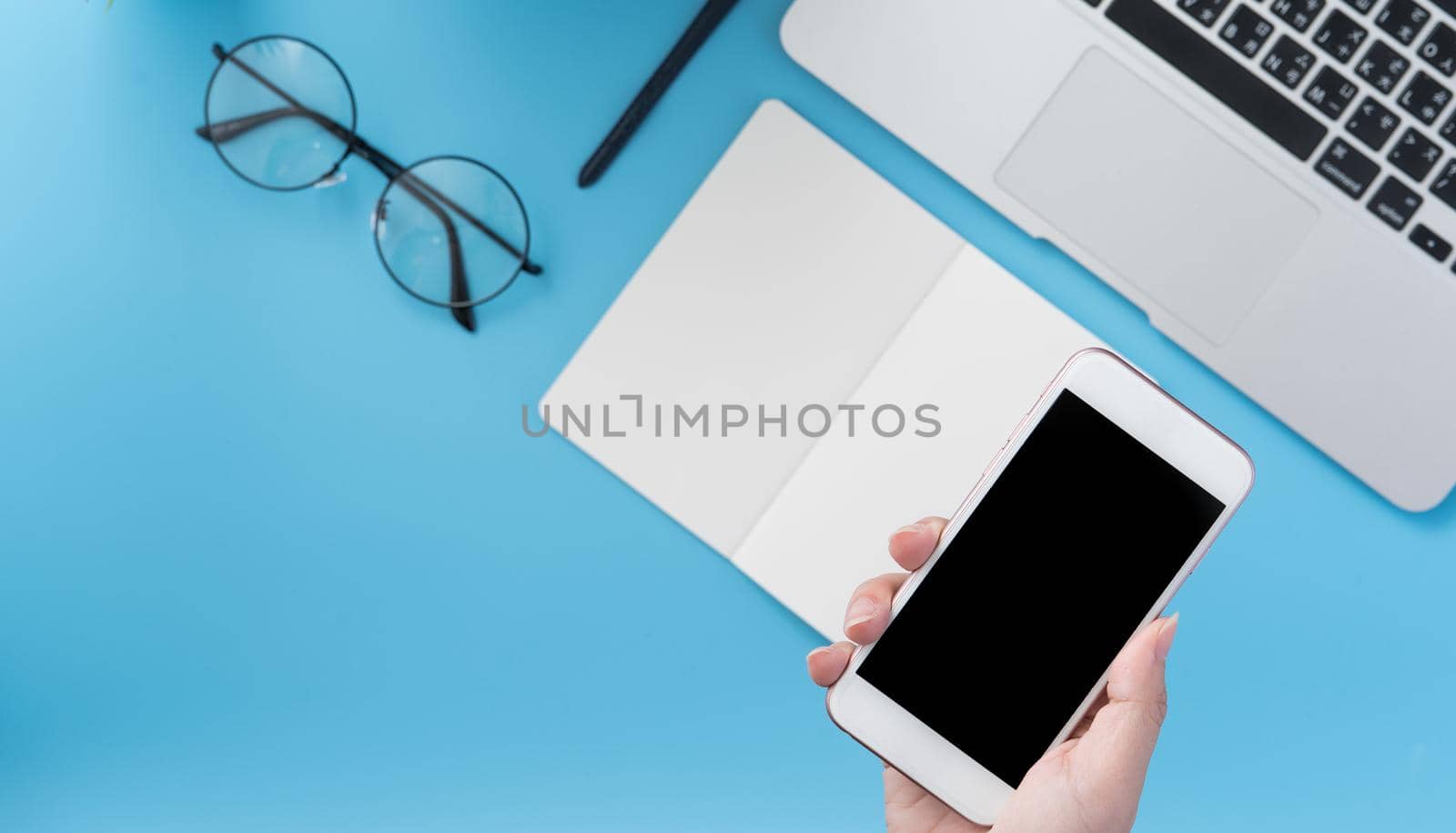 Social network connecting office table concept with fashion accessories, minimal interior with a woman holding smartphone, top view, flat lay, mockup, copy space