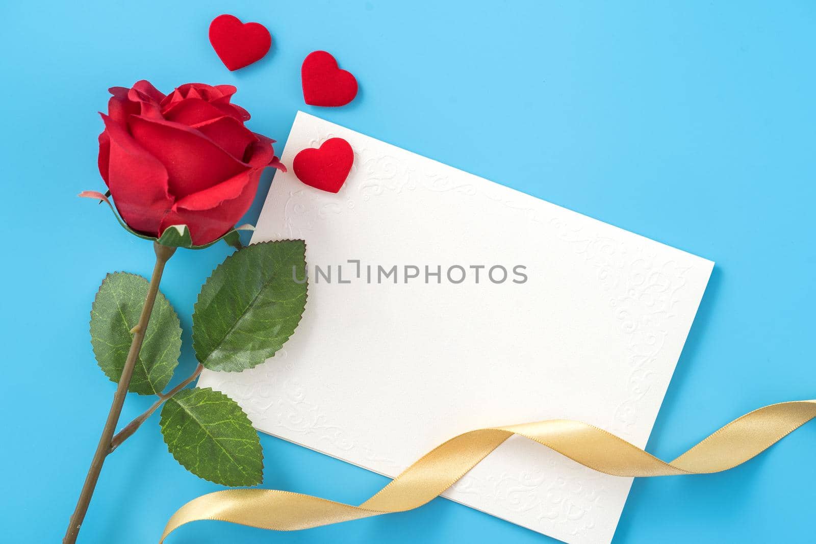 Beautiful greeting card with golden ribbon for Valentine's day, anniversary, mother's day and birthday on blue background, copyspace, topview, mockup, flatlay
