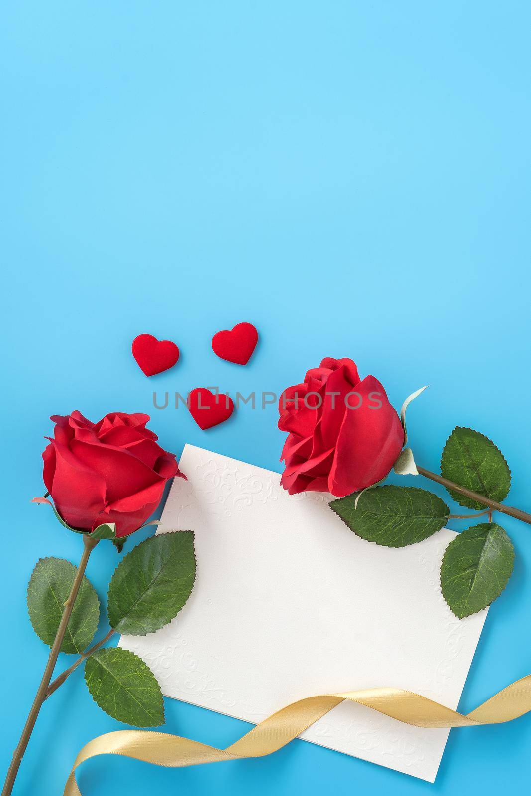 Beautiful greeting card with golden ribbon for Valentine's day, anniversary, mother's day and birthday on blue background, copyspace, topview, mockup, flatlay by ROMIXIMAGE